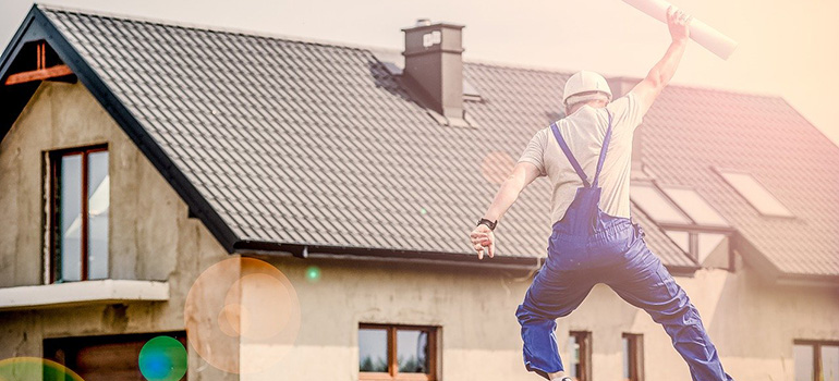 A worker jumping in front of a finished house